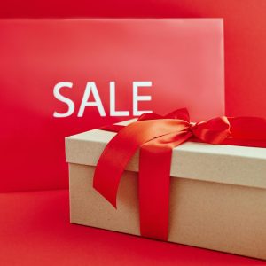 Cardboard Box with Red Ribbon Beside A Sale Sign